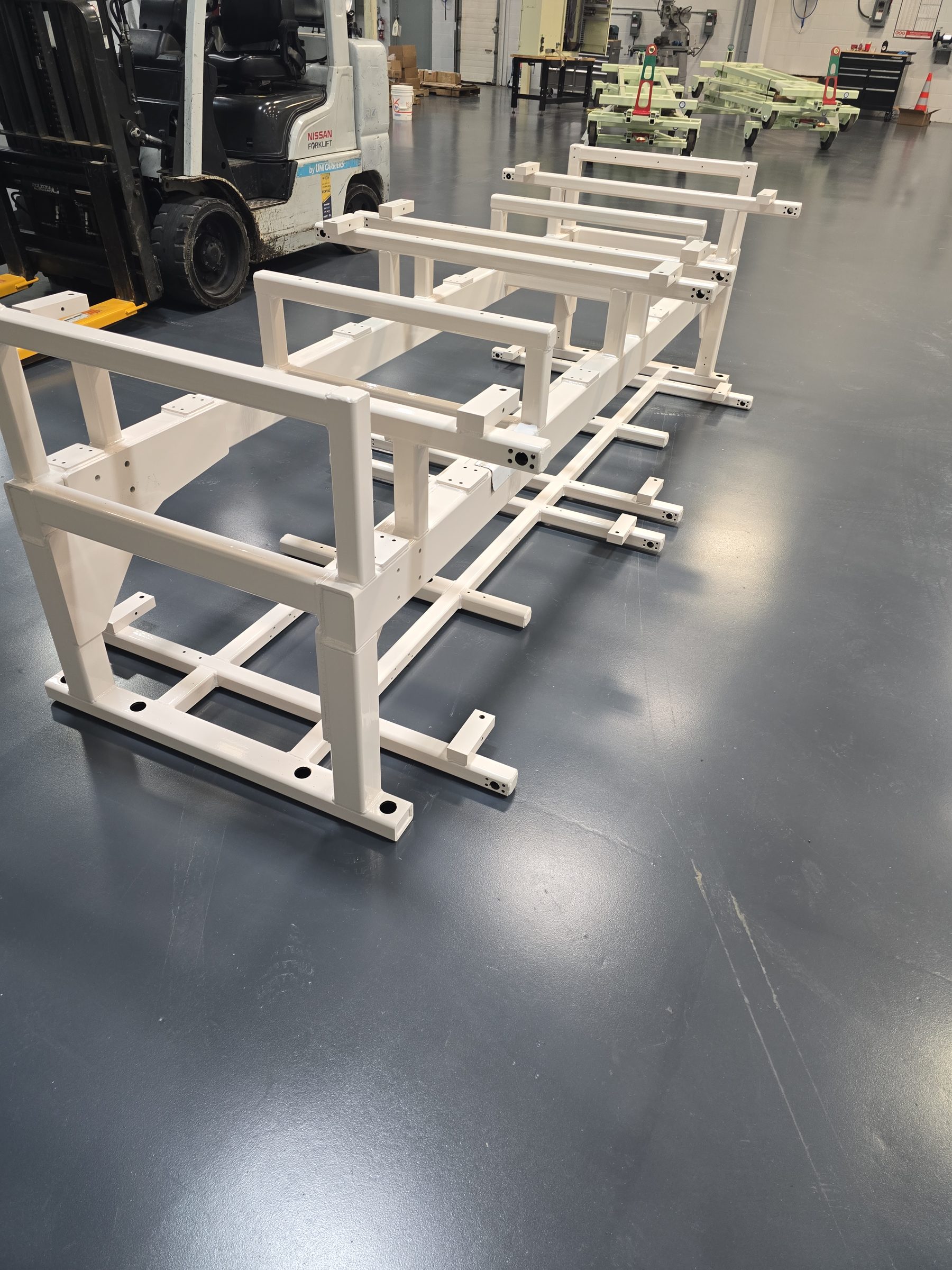 Powder-coated machine frames lined up on the shop floor after finishing