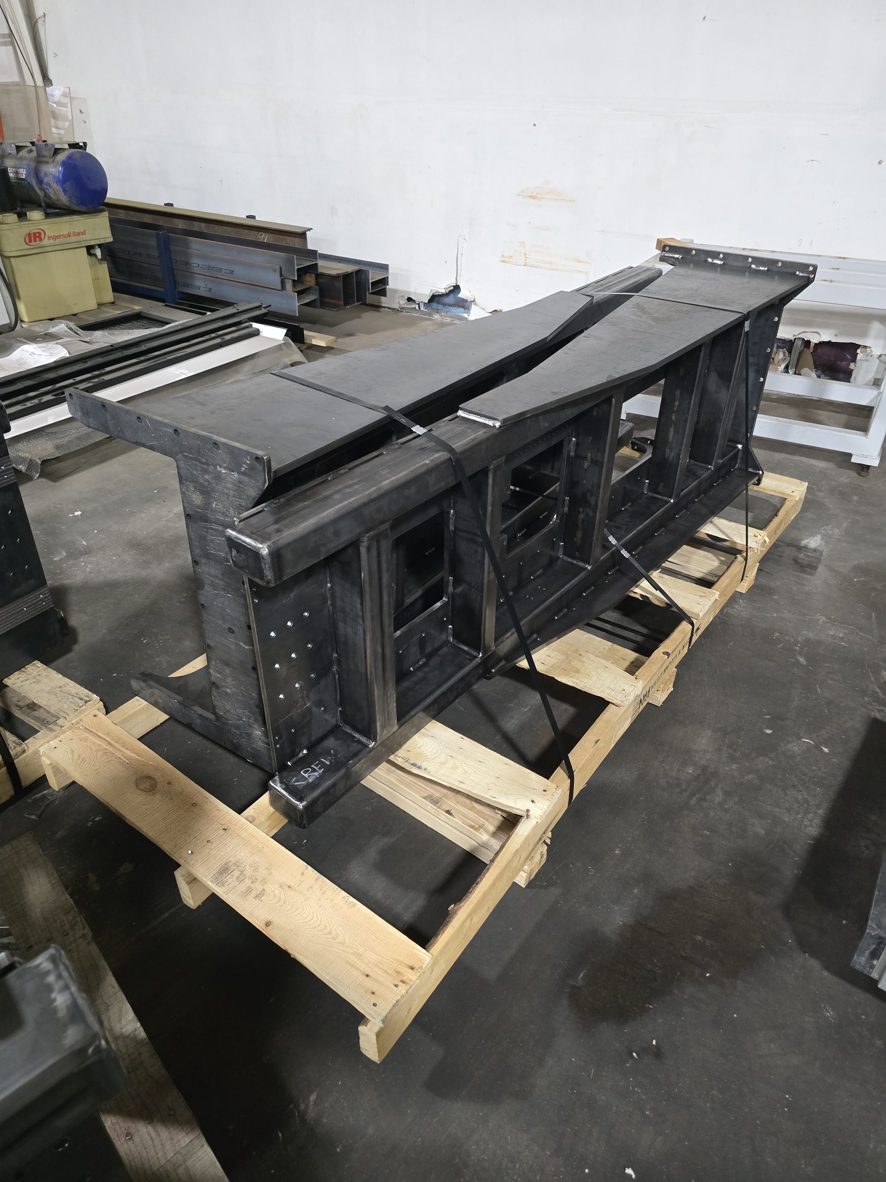 Welded steel frame strapped to a pallet awaiting finishing